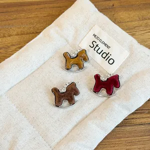 Detailed view of three elegant flocked horse brooches with rhinestones on a linen pouch