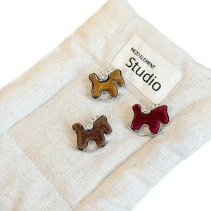 Three flocked rocking horse brooches in yellow, brown, and burgundy with rhinestones.