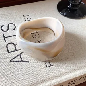 Bracelet jonc minimaliste irrégulier en résine marbrée crème et marron posé sur un livre