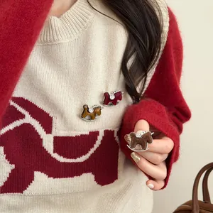 Close-up of three colorful flocked rocking horse brooches with sparkling diamonds on a sweater
