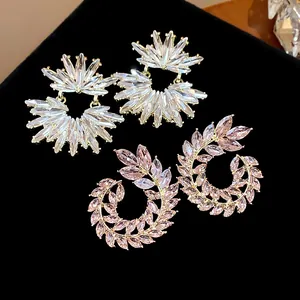 Close-up of sparkling crystal wheat ear and floral stud earrings on black velvet