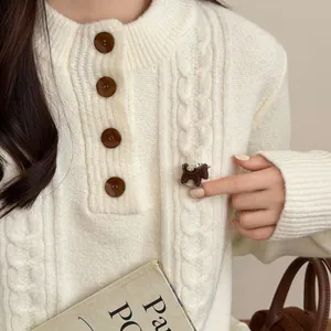 Detailed view of a brown flocked rocking horse brooch with rhinestones on a white sweater.