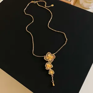 Close-up detail of a gold plated necklace with three filigree flower pendants.
