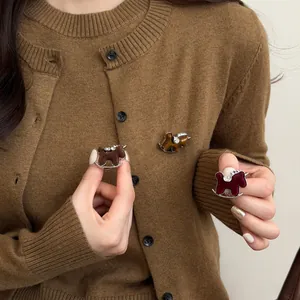 Detailed view of elegant flocked rocking horse brooches with rhinestones on a brown cardigan