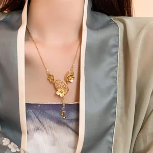 Close-up view of an elegant gold-plated Chinese style flower tassel necklace on a model.