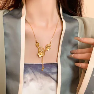 Detail of gold-plated Chinese style necklace with flower and tassel motifs on a model.