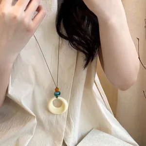 Long resin sweater necklace featuring a round hollow pendant in minimalist vintage style