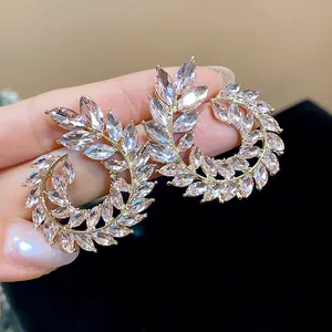 Close-up detail of sparkling marquise-cut crystal wheat stalk earrings in gold finish