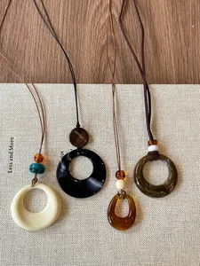 Detail of four resin sweater necklaces in earth tones with hollow circular designs