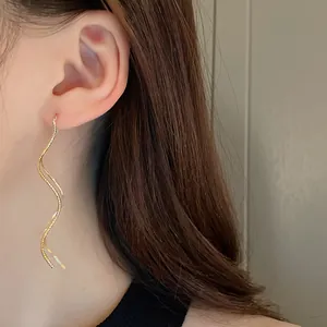 Close-up of elegant gold plated wave geometric dangling ear threads on ear