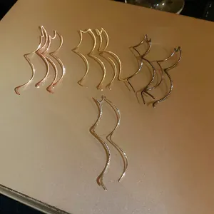 Close-up of minimalist wavy geometric earrings in gold, silver, black, and rose gold.