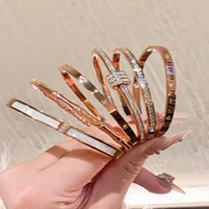 Close-up detail of several rose gold bangles featuring crystals and shell inlay