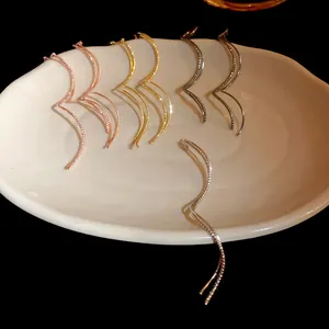 Detailed close-up of wavy geometric ear threads in gold, silver, and rose gold finishes