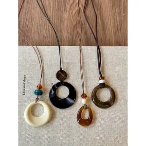 Close-up of four retro geometric resin pendant necklaces with minimalist cord design