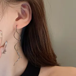 Close-up of elegant silver wave-shaped geometric spiral earrings on a model
