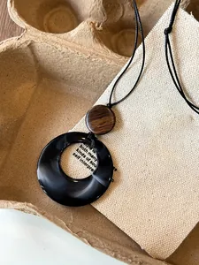 Detail view of a retro black marbled resin circle and wood bead necklace on textured canvas