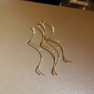 Close-up of elegant gold-plated wavy ear threads with shimmering metallic texture