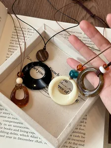 Close-up of circular resin pendants in white, black, and amber on vintage book background