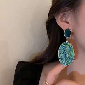 Eleganti orecchini a pendente geometrici vintage con finitura iridescente su modella