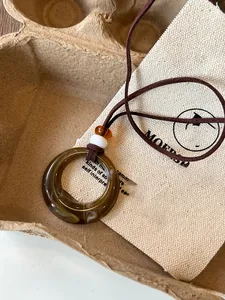 Detail of vintage resin round pendant necklace with ethnic beads on brown cord.