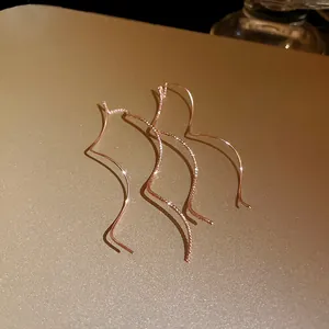 Detailed view of elegant rose gold wavy geometric threader earrings with sparkling texture