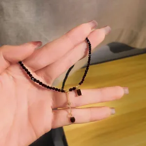 Close-up detail of an elegant dark crystal bead necklace with golden pendant held in a hand