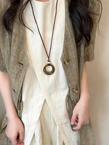 Detail of a vintage resin circular pendant necklace paired with a linen ethnic vest.