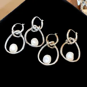 Detalle de pendientes de aro plateados con perlas barrocas sobre terciopelo negro