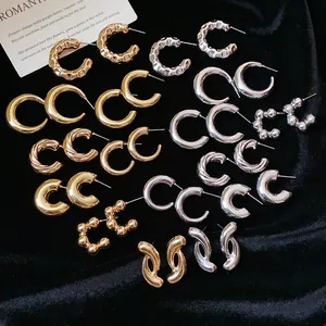 Collection of various C-shaped gold and silver hoop earrings on black velvet