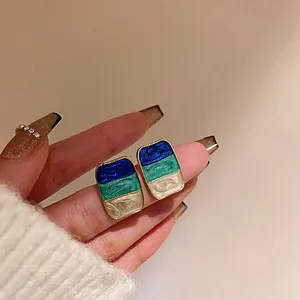 Primo piano di orecchini geometrici vintage con smalto tricolore in blu e verde