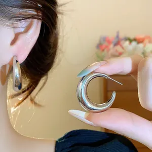 Close-up of minimalist silver C-shaped hoop earrings for a chic, modern look.