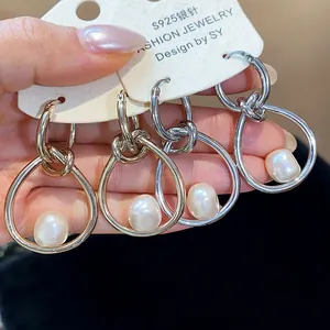 Detalle de pendientes de aro anudados plateados con perlas irregulares y agujas S925.