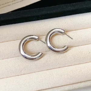 Close-up of elegant silver C-shaped hoop earrings displayed on a soft jewelry tray