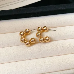 Close-up of minimalist gold-plated C-shaped bead earrings on jewelry tray