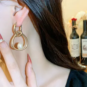Primer plano detallado de elegantes pendientes de aro dorados con perla en una modelo