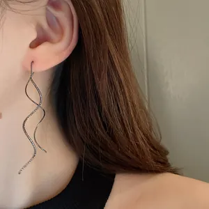 Close-up detail of elegant minimalist wave-shaped geometric ear line earrings on model