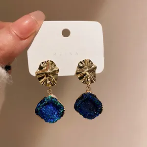 Dettaglio della trama metallica e delle pietre blu brillanti di questi orecchini.