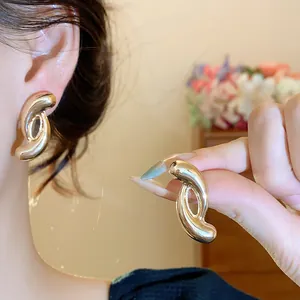 Close-up of gold-finish twisted C-shaped stud earrings showcasing metal texture and design.