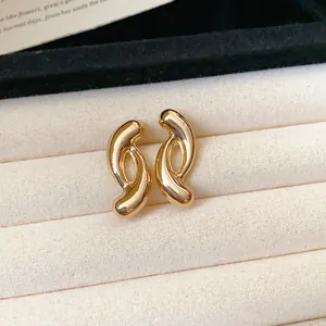 Close-up of minimalist gold twisted C-shape stud earrings on a velvet display tray