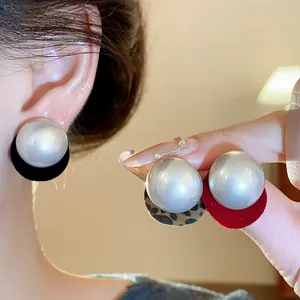 Close-up of pearl stud earrings with black, red, and leopard print backings