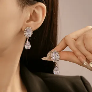 Détail de boucles d'oreilles argentées en forme de goutte avec zircons sur mannequin.