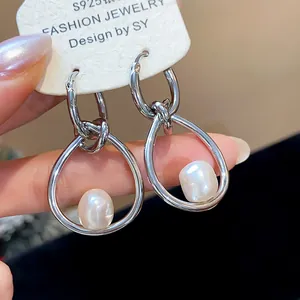 Primer plano detallado de pendientes de aro plateados con perlas blancas puras