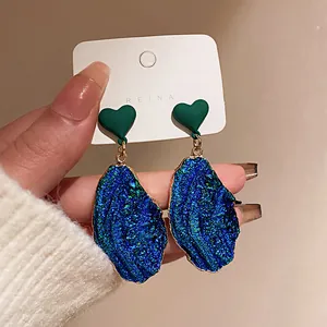 Primo piano dettagliato di orecchini druzy blu con dettaglio di perno a cuore verde