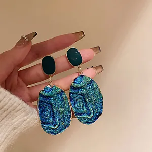 Primo piano di orecchini vintage geometrici con una trama blu iridescente unica.