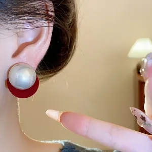 Detailed view of elegant silver needle round pearl stud earrings with red velvet base