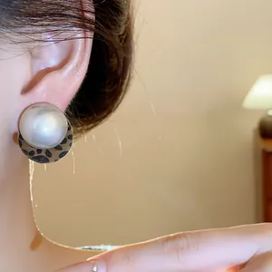 Close-up of a stylish leopard print pearl earring worn on ear with soft warm lighting