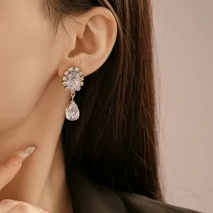 Détail en gros plan d'élégantes boucles d'oreilles en zircon violet portées par un modèle