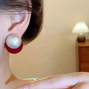 Elegant macro detail of a pearl stud earring with red velvet backing worn on ear