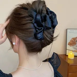Dettaglio di una grande clip per capelli in raso nero in un'elegante acconciatura raccolta.