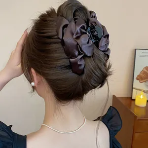 Vista dettagliata di un'elegante pinza per capelli a fiore in raso marrone su uno chignon.